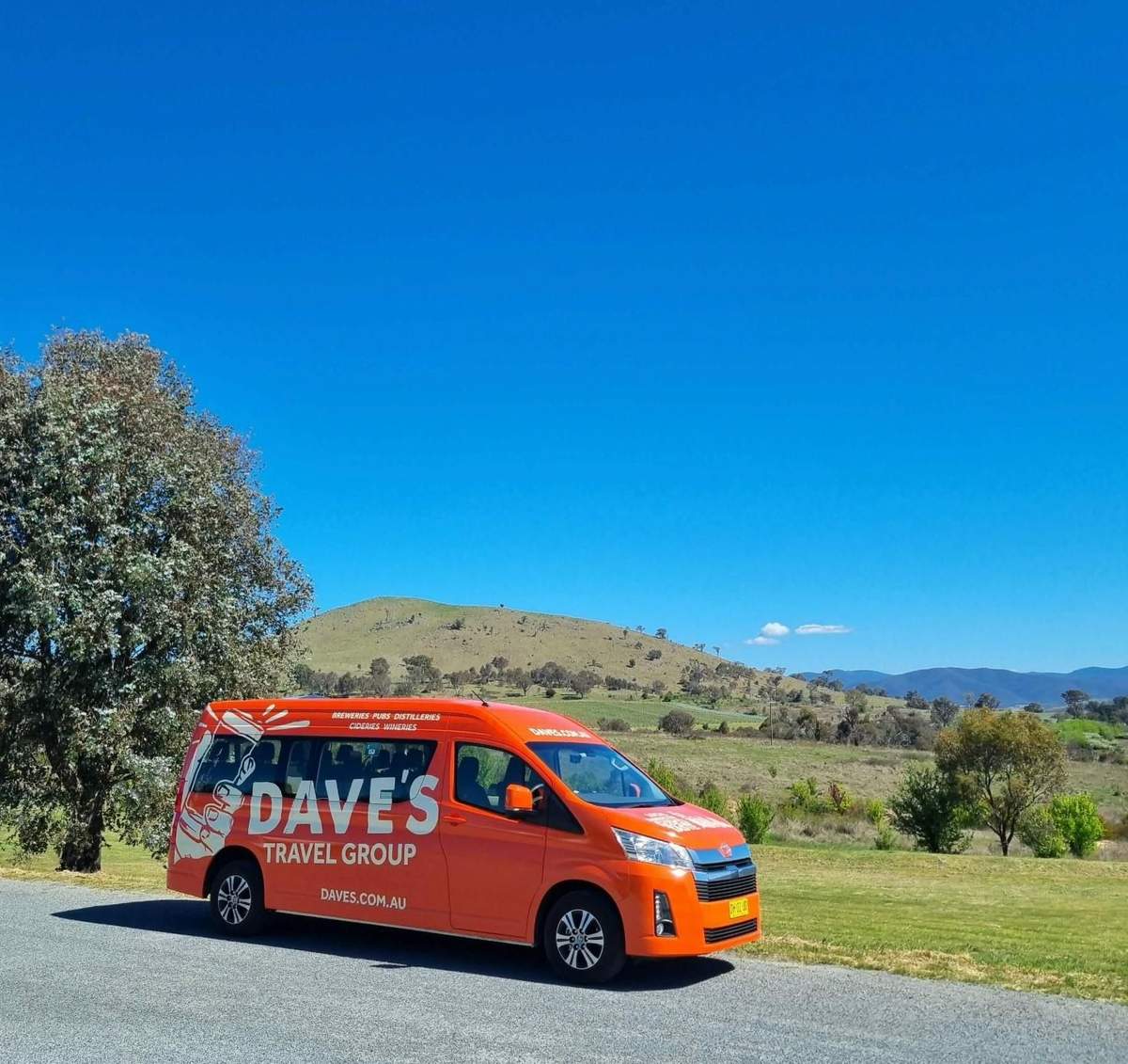 Hunter Valley: Guided Wine Tour from Newcastle + Lunch + Tastings An orange van with 'Dave's Travel Group' branding parked on a roadside, with a scenic countryside landscape in the background.