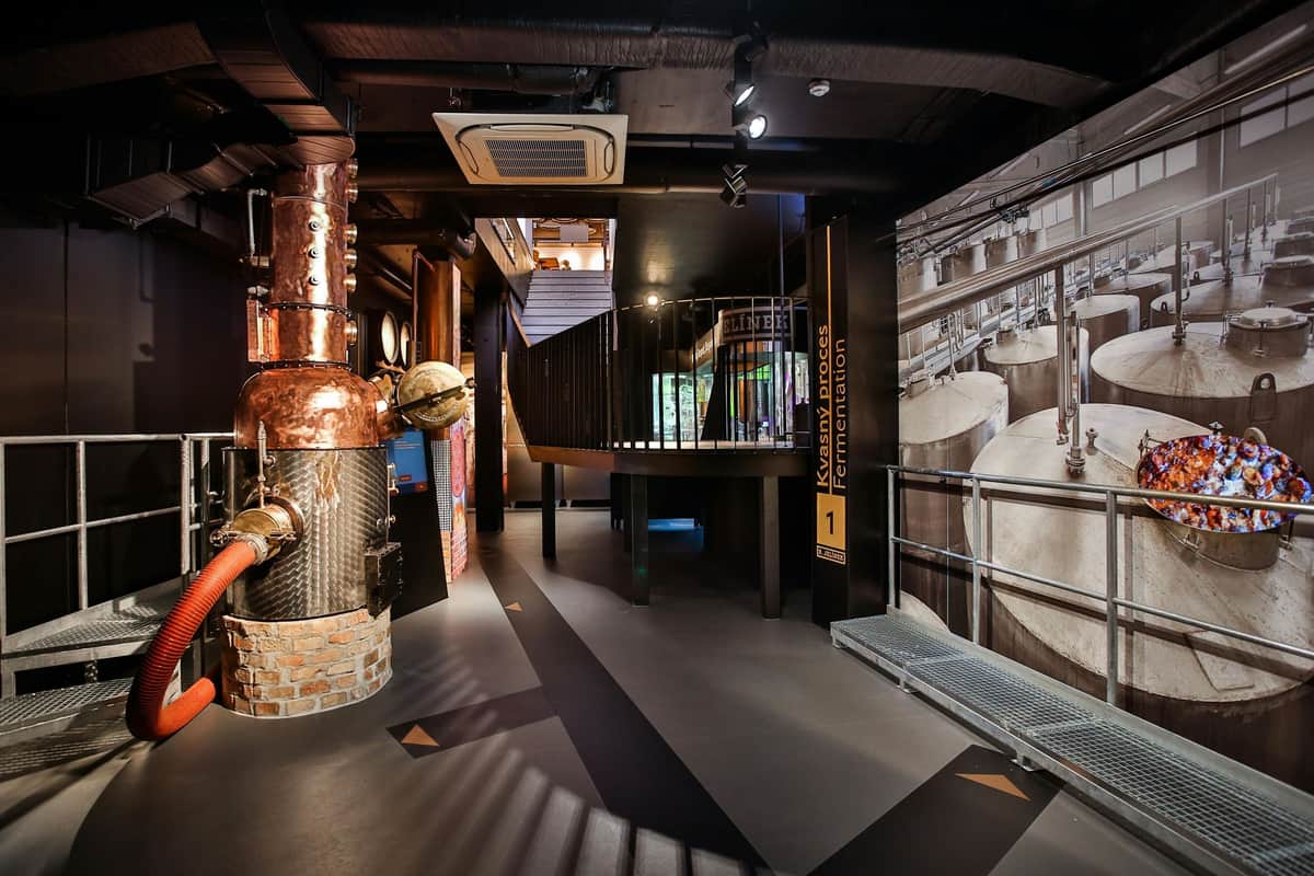 Slivovitz Museum: Entry Ticket + 5D VR Show + Tastings Interior of an industrial exhibit with copper pipes, fermentation tanks, a staircase, and informative signs.