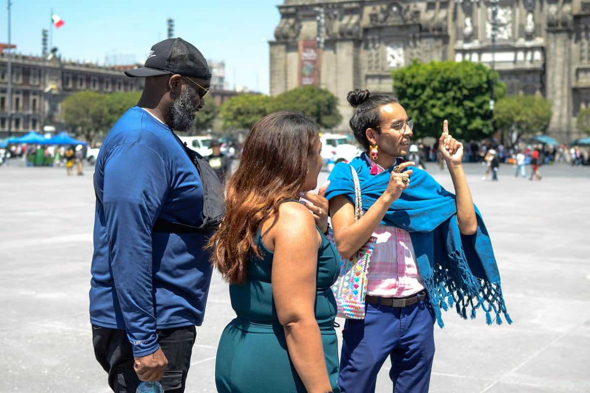 Mexico City: Zocalo Tacos Tour by Michelin-Star Chef Torres A guide passionately explains local history to two guests in the heart of the Zócalo.