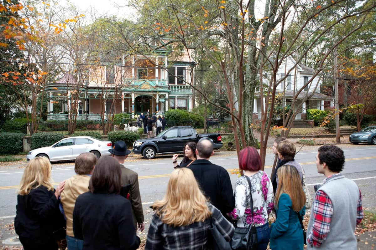 Atlanta Beltline & Inman Park: Food, Art & History Tour A group of people standing on a sidewalk looking at a large, ornate house across the street on a sunny day.