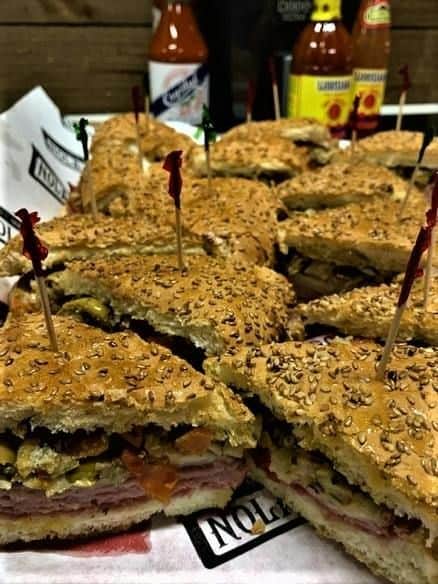 Gros plan sur des sandwichs au sésame coupés en morceaux, garnis de charcuterie et de légumes, maintenus par des cure-dents.