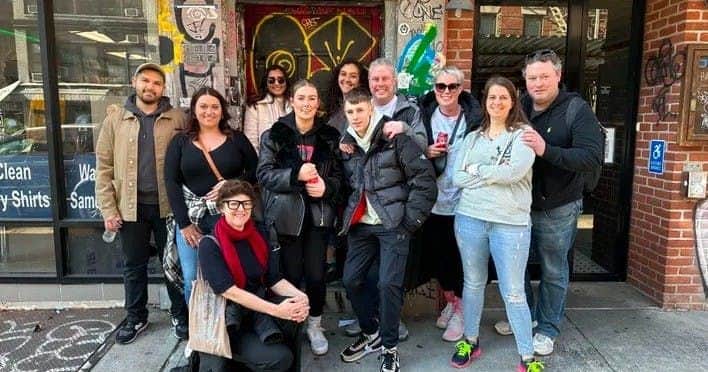 A group of people posing together in front of a graffiti-covered entrance in an urban setting, smiling for the photo.