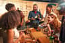 A group of people enjoying a whiskey-tasting session at a distillery, with a presenter holding a bottle of Jameson.